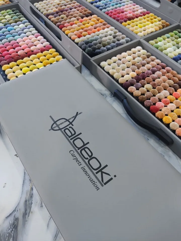 Bandejas de muestras de color en forma de pompón, cientos de tonos, junto a la caja de muestras de Aldeoki
