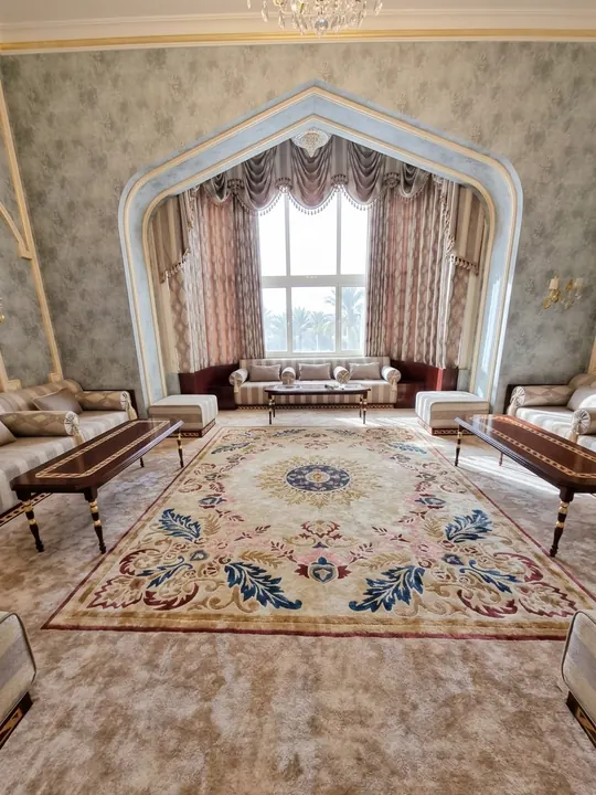 Salón con un gran arco y una alfombra floral en crema, azul y granate sobre moqueta