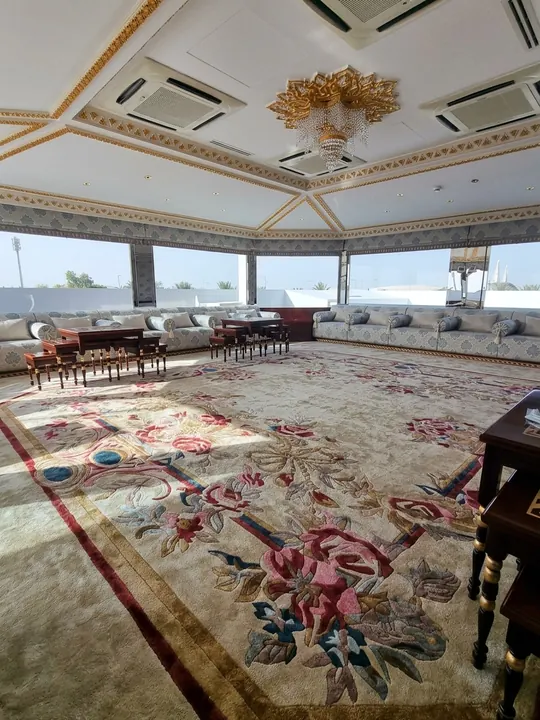 Salón alargado con una gran alfombra floral en crema y rosa sobre moqueta