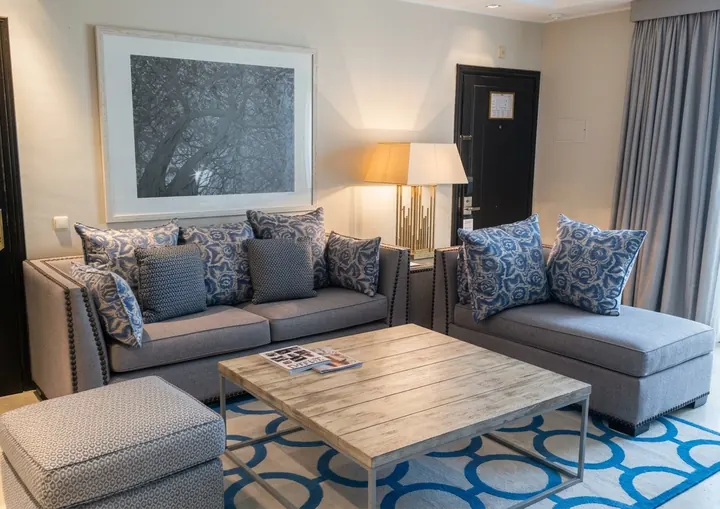 Salón de suite con alfombra de círculos entrelazados en azul sobre fondo crudo