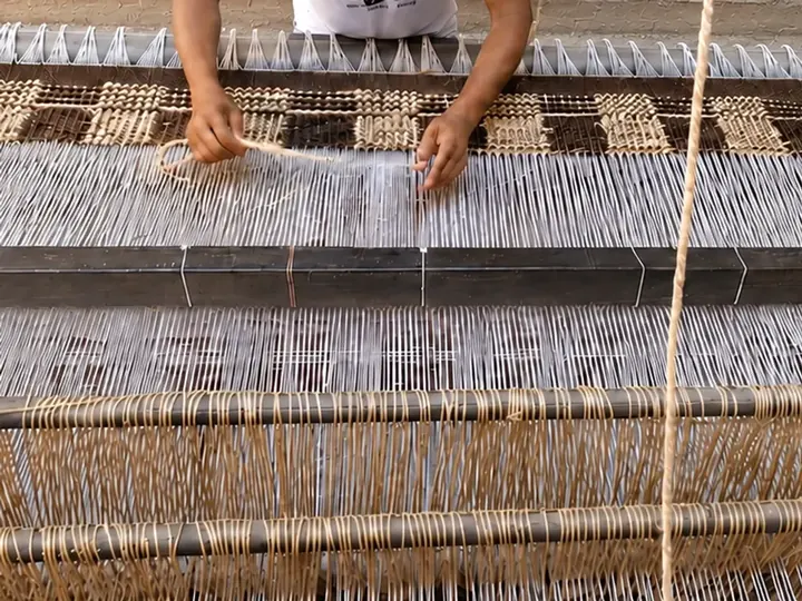 Artesanos tejiendo una alfombra a mano en un telar vertical